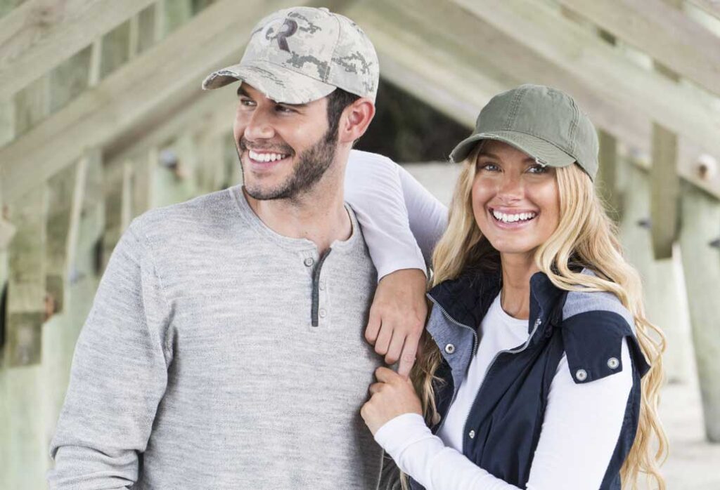 cute couple wearing branded ball caps and vest outerwear.